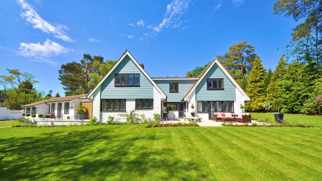 Ein schönes, modernes Haus steht auf einem großen, grünen Grundstück. Symbolbild: Wohngebäudeversicherung bei maxXse Versicherungsmakler in Nürnberg.